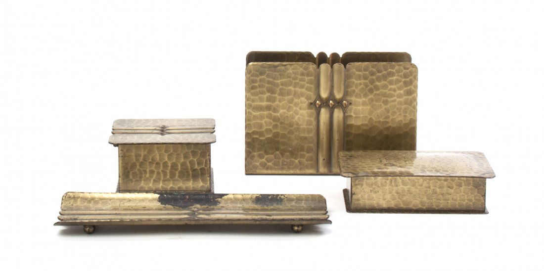 A Roycroft Brass Washed Hammered Copper Desk Set, Lengt: A Roycroft Brass Washed Hammered Copper Desk Set, comprising a pen tray, a letter rack, an ink pot and a stamp box, each bearing an orb and cross mark to base. Length of first 6 7/8 inches. Property f