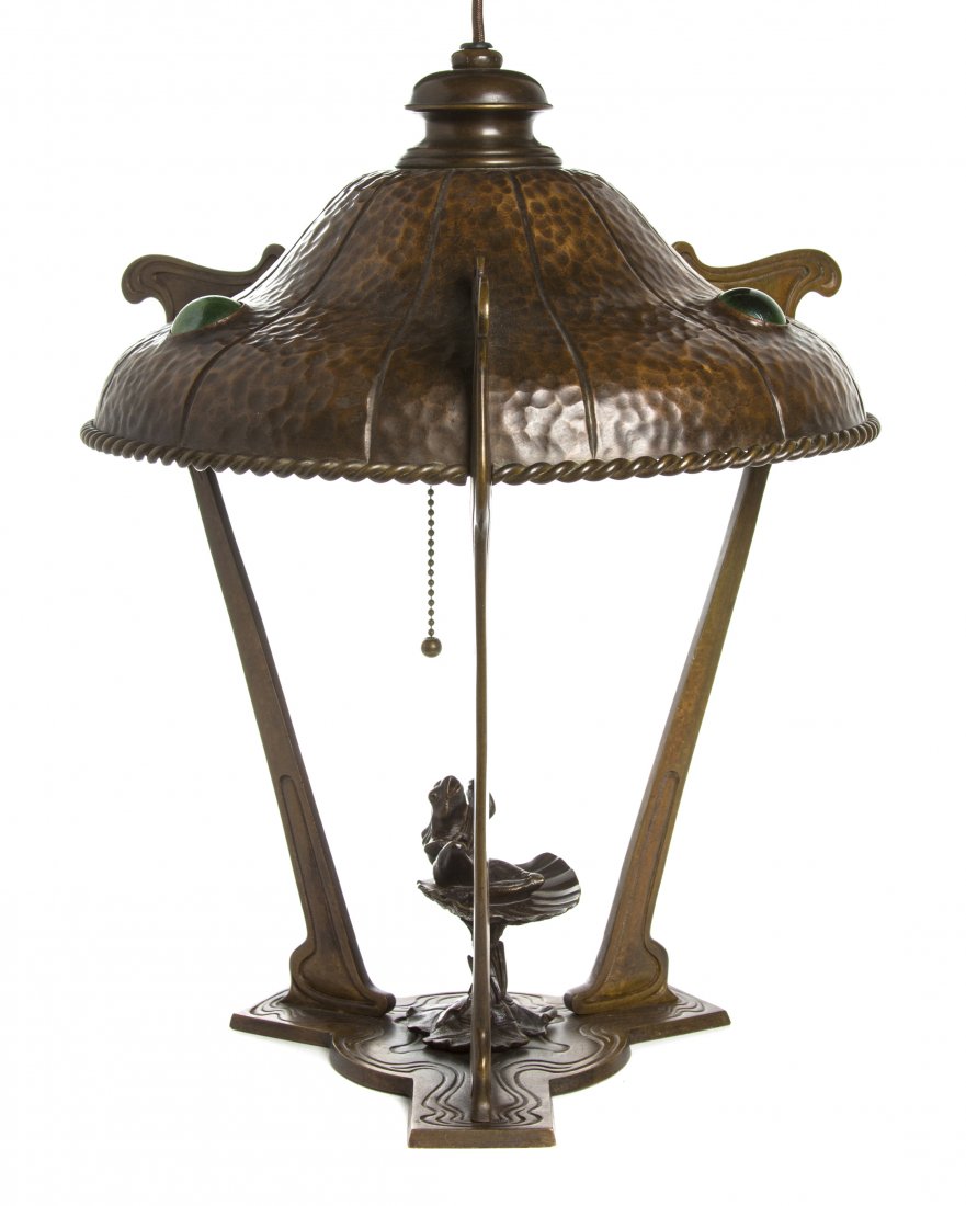 An Austrian Transitional Arts and Crafts/Art Nouveau Co: An Austrian Transitional Arts and Crafts/Art Nouveau Copper Table Lamp, the hand hammered shade raised on three supports joined by a tripartite base, centered with a frog sitting on a shell and playin