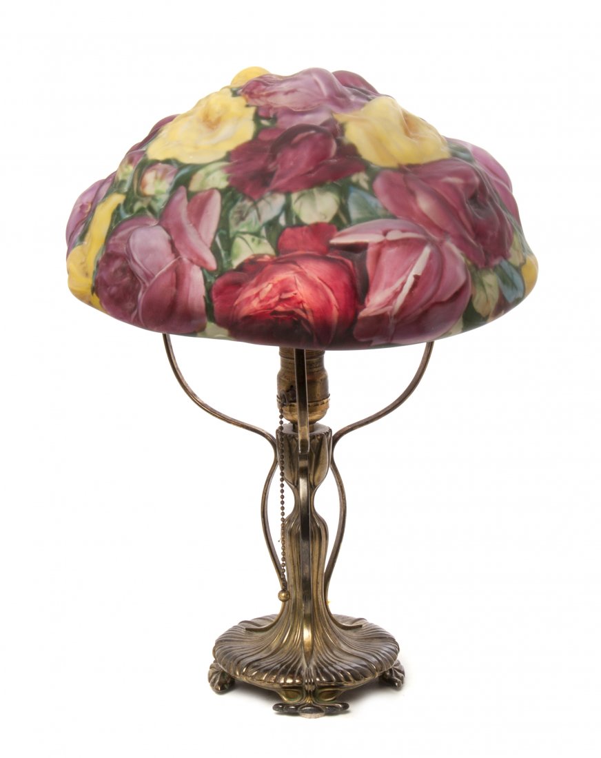 A Pairpoint Puffy Reverse Painted Glass Table Lamp, Dia: A Pairpoint Puffy Reverse Painted Glass Table Lamp, having a rose decorated shade in yellow and pink, raised on a cast metal Pairpoint base. Diameter of shade 13 x height overall 18 inches.