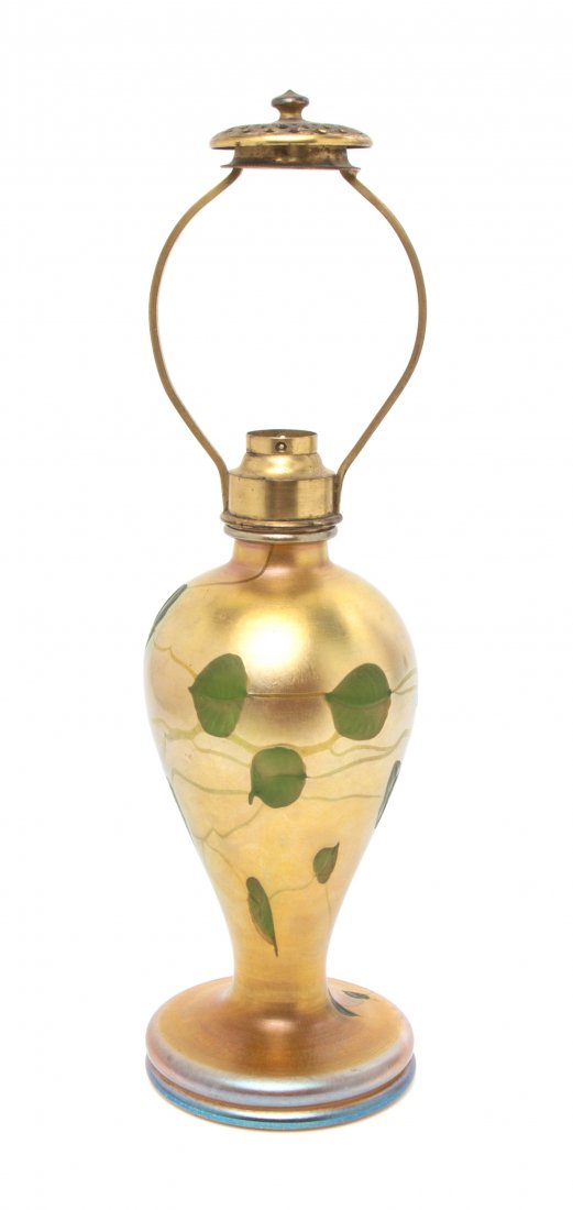 A Tiffany Studios Wheel Carved Gold Favrile Glass Lamp,: A Tiffany Studios Wheel Carved Gold Favrile Glass Lamp, of baluster form with green leaf and vine decoration and gilt metal mounts, signed L.C. Tiffany - Favrile. Height overall 15 inches.