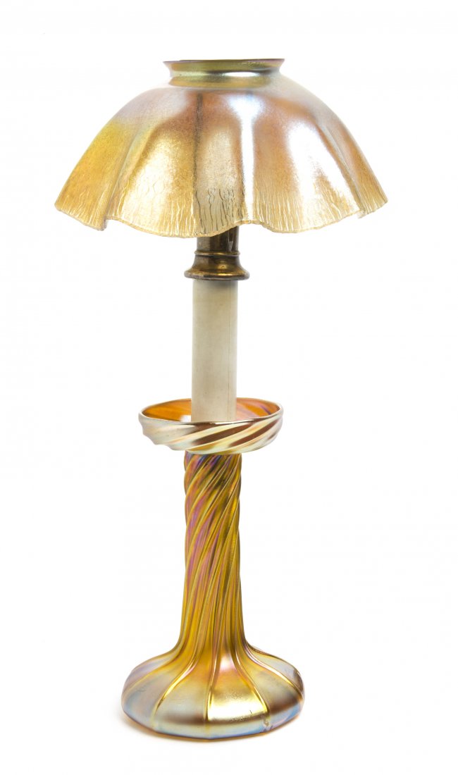 A Tiffany Studios Gold Favrile Glass Candlestick Lamp, : A Tiffany Studios Gold Favrile Glass Candlestick Lamp, having a ruffled shade over the silvered and composite insert, raised on a twisted base, the shade and base signed L.C.T. Height 14 3/8 inches.