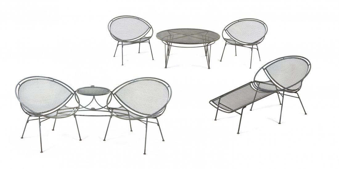 A John B. Salterini Wrought Iron Patio Suite, Height of: A John B. Salterini Wrought Iron Patio Suite, comprising a chaise with a removable ottoman, two chairs, a table and a tete-a-tete, each of hoop form with a mesh back and seat, raised on tubular legs.