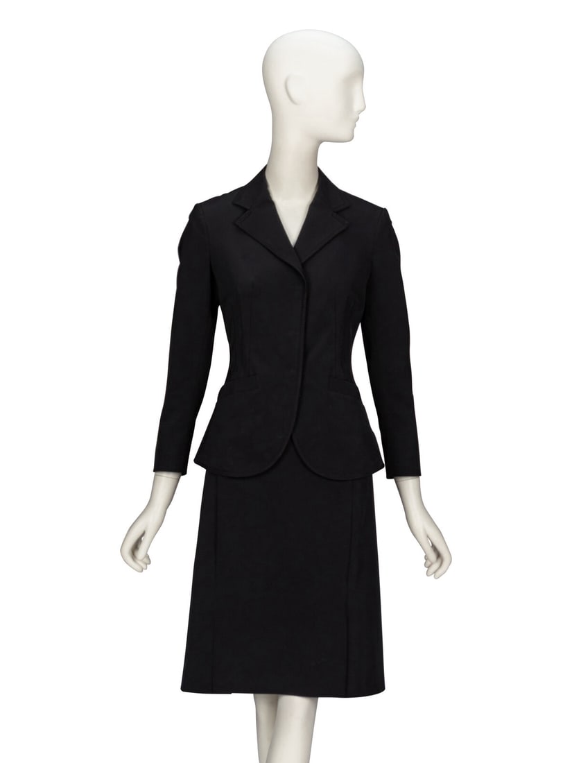 PRADA, BLACK TWILL SKIRT SUIT: PRADA, BLACK TWILL SKIRT SUIT THE FIRST Fitted suit jacket in black polyester/elastane-blend twill. Decorative topstitching throughout. Notched lapels. Wrist-length set-in sleeves with concealed snap