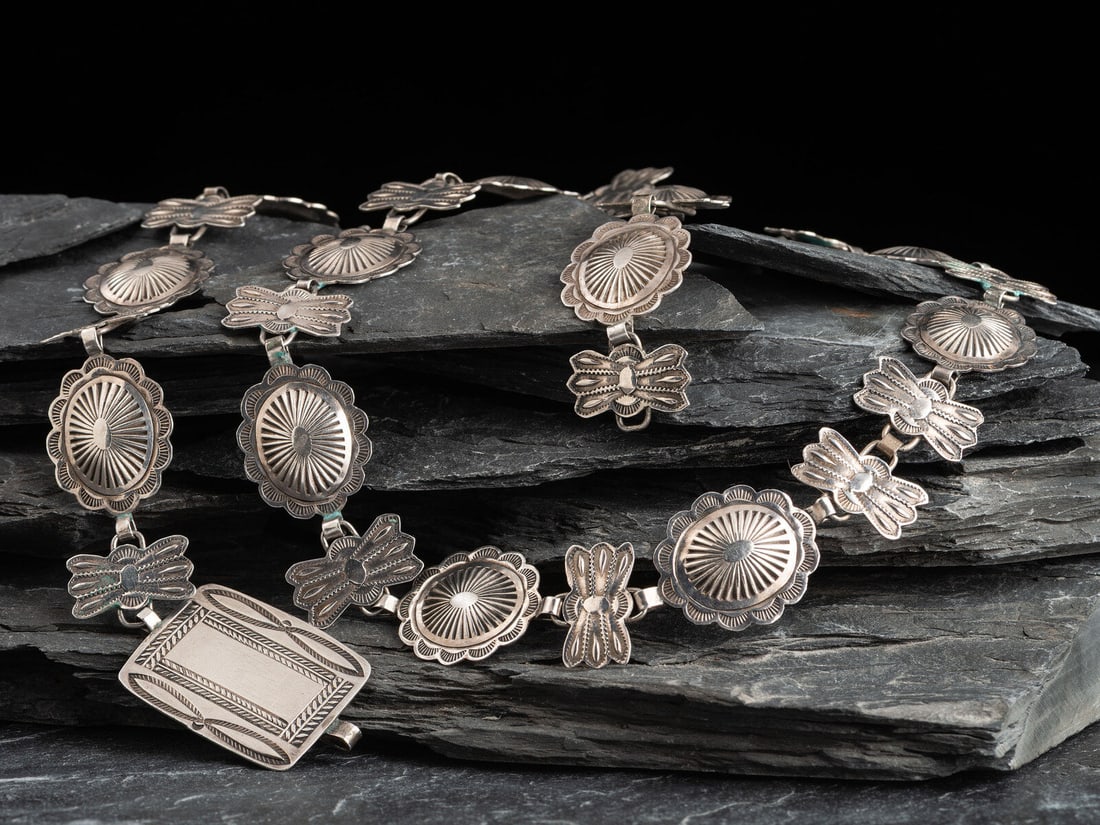 Etsitty Tsosie (Diné, c. 1880-1937) Petite Stamped Silver Link Concha Belt: Etsitty Tsosie (Diné, c. 1880-1937) Petite Stamped Silver Link Concha Belt sixteen butterflies alternate with fourteen oval conchas, terminating in a rectangular buckle; marked with artist's cros