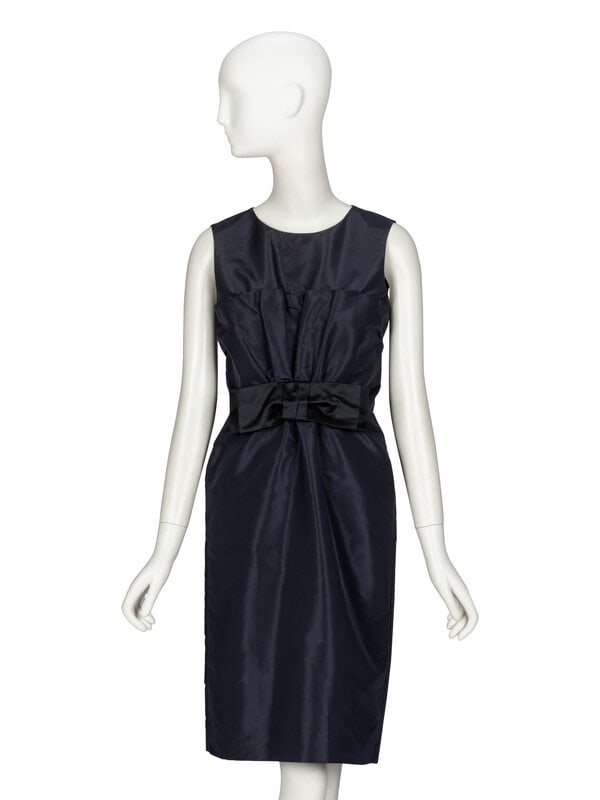 Prada, Faille Sheath Dress: Prada, Faille Sheath Dress Sleeveless sheath dress in midnight blue silk-blend faille. Round neckline. Draped pleats at bodice front; tied black satin bow at front waist. Ruching at back bodice.