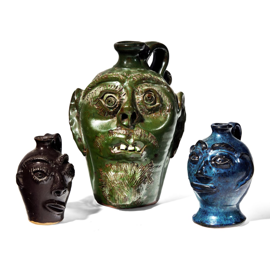 Bobby Ferguson and Stanley Ferguson, Three Glazed Stoneware Face Jugs: Bobby Ferguson and Stanley Ferguson, Three Glazed Stoneware Face Jugs Gillsville, Georgia, Late 20th / Early 21st Century comprising a jug in green glaze by Bobby Ferguson, signed and dated to