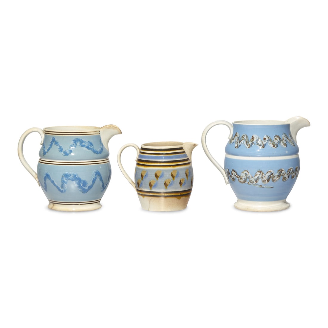 A Group of Three Mochaware Pitchers: A Group of Three Mochaware Pitchers England, 19th Century the larger pitchers with "worming" decoration and the smaller pitcher with banding and "Cat's Eye" decoration; together with two Mochaware bow