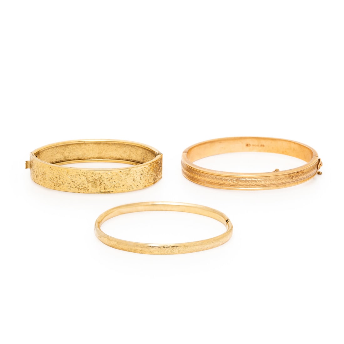 COLLECTION OF THREE YELLOW GOLD BANGLE BRACELETS: COLLECTION OF THREE YELLOW GOLD BANGLE BRACELETS Including three bangle bracelets, all hinged with side clasps. 14 karat yellow gold, yellow gold, and low-karat yellow gold. 7 7/8 inches inner circumf