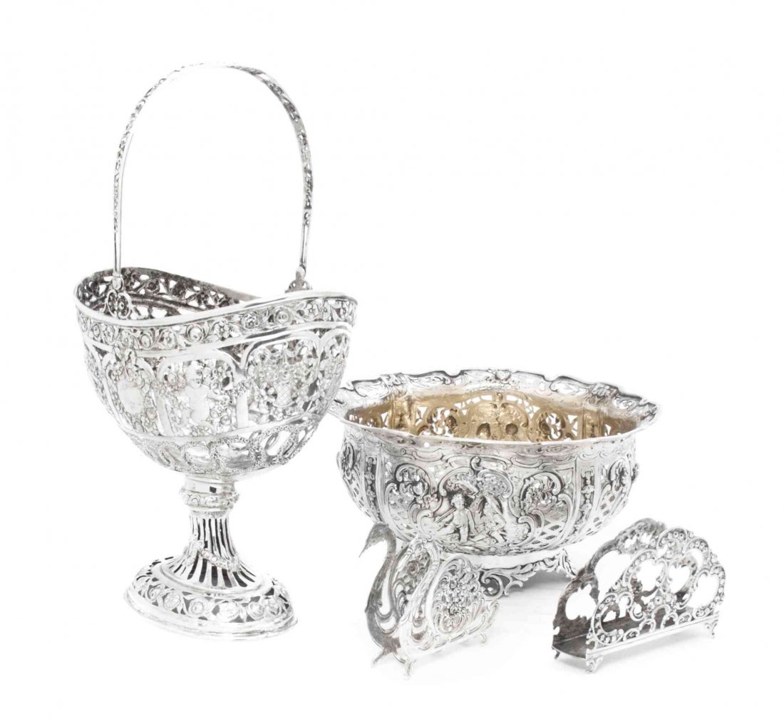 Two German Silver Reticulated Baskets, Height of talles: Two German Silver Reticulated Baskets, one of footed oval form with a swing handle decorated with winged putti and floral festoons, the other of circular form with cartouches depicting putti allegoric