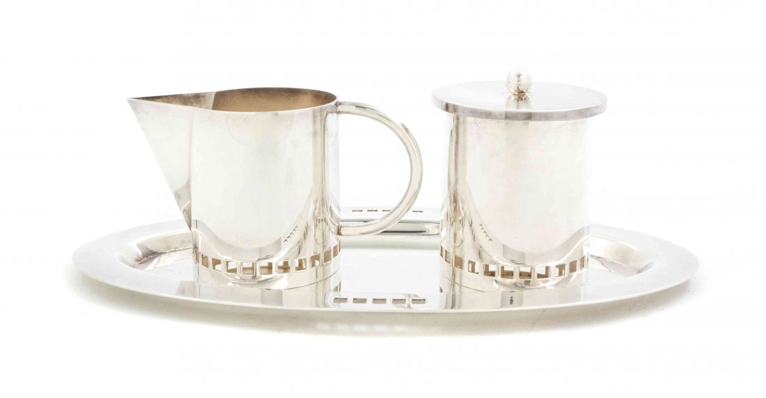 An Italian Silverplate Creamer and Sugar Set, Richard M: An Italian Silverplate Creamer and Sugar Set, Richard Meier for Swid Powell, comprising a creamer, a covered sugar bowl, with a cobalt liner, and an oval tray, each with pierced geometric decoration.