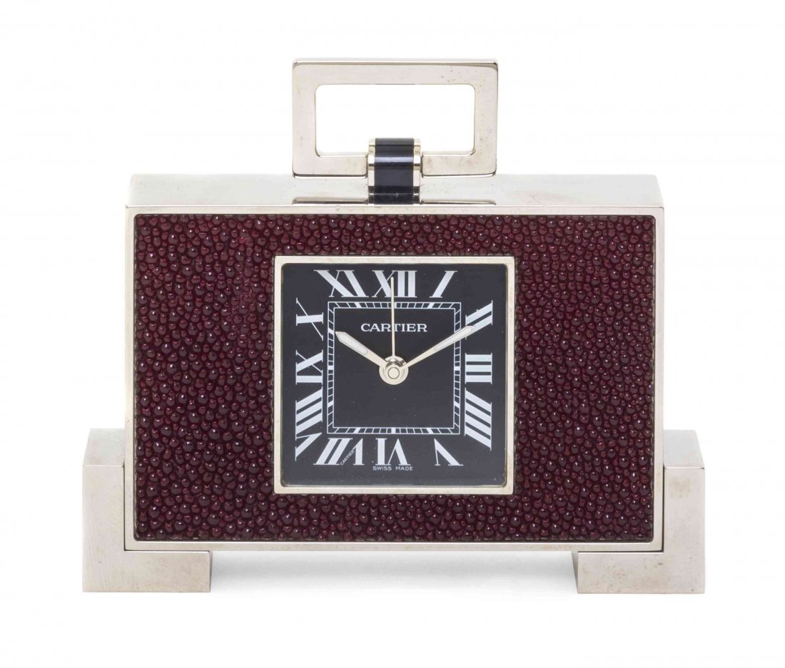 A Cartier Chromed, Enameled and Shagreen Desk Clock, Wi: A Cartier Chromed, Enameled and Shagreen Desk Clock, the swing handle over the rectangular case, set with a square dial having Roman numerals, raised on L-form feet, numbered 180501GD, 2749, with the 