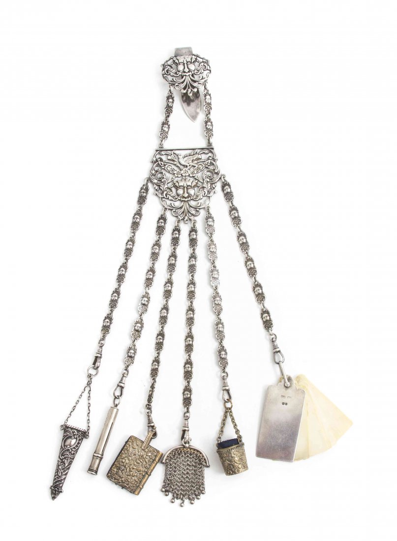 A English Silverplate Chatelaine, Length overall 14 3/4: A English Silverplate Chatelaine, having a pierced mask clip over the central section decorated with pierced foliate, bird and grotesque mask decoration, hung with six chains each with conforming deco