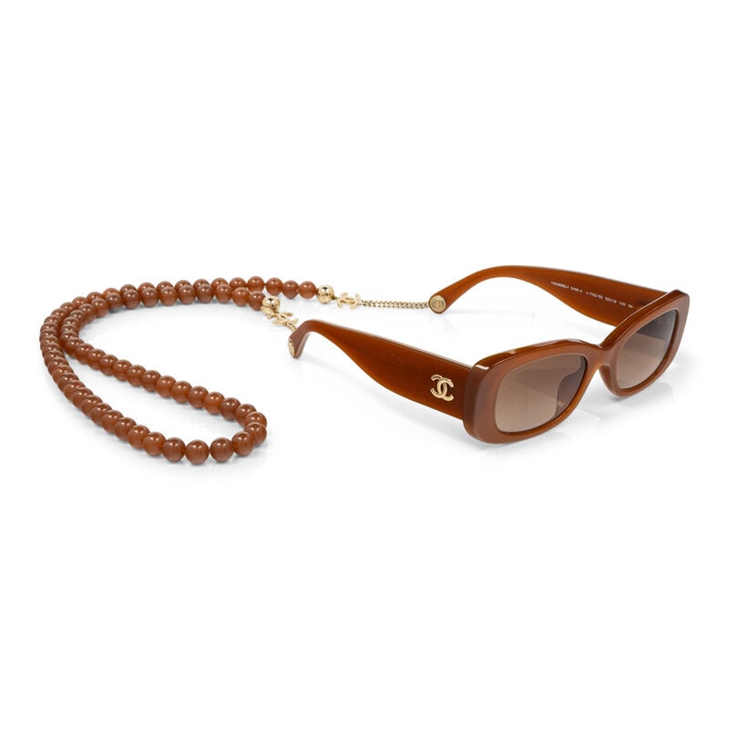 CHANEL, SUNGLASSES & BEADED CHAIN: CHANEL, SUNGLASSES & BEADED CHAIN Rectangular sunglasses in amber-colored acetate with gold-tone metal hardware. With removable matching acetate bead & metal glasses chain. Label: Chanel