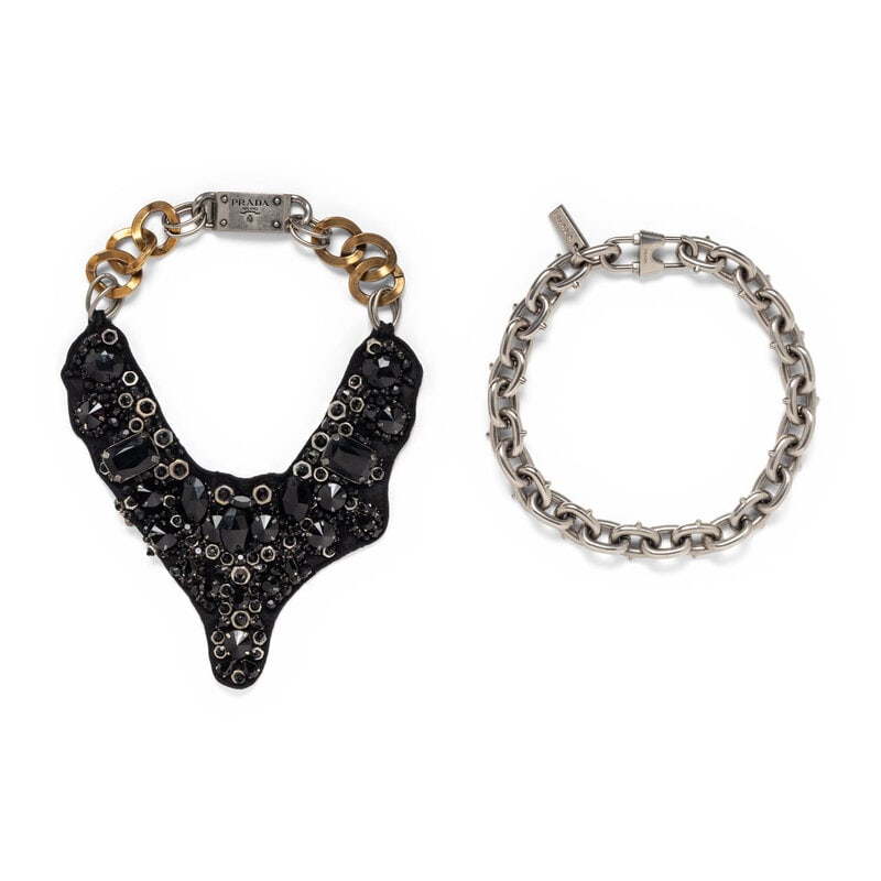 PRADA, TWO NECKLACES: PRADA, TWO NECKLACES THE FIRST Chain & bib necklace in aged gold-tone and aged silver-tone metals; with a black textile bib embellished with black rhinestones. Box clasp closure. Stamped "PRADA /