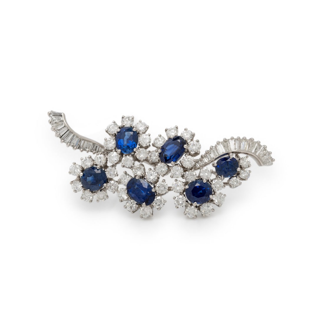 CARTIER, DIAMOND AND SAPPHIRE BROOCH: CARTIER, DIAMOND AND SAPPHIRE BROOCH In a foliate design, featuring a cluster of oval cut sapphire flowers amidst a swirl of round and baguette cut diamonds weighing approximately 4.30 carats total.