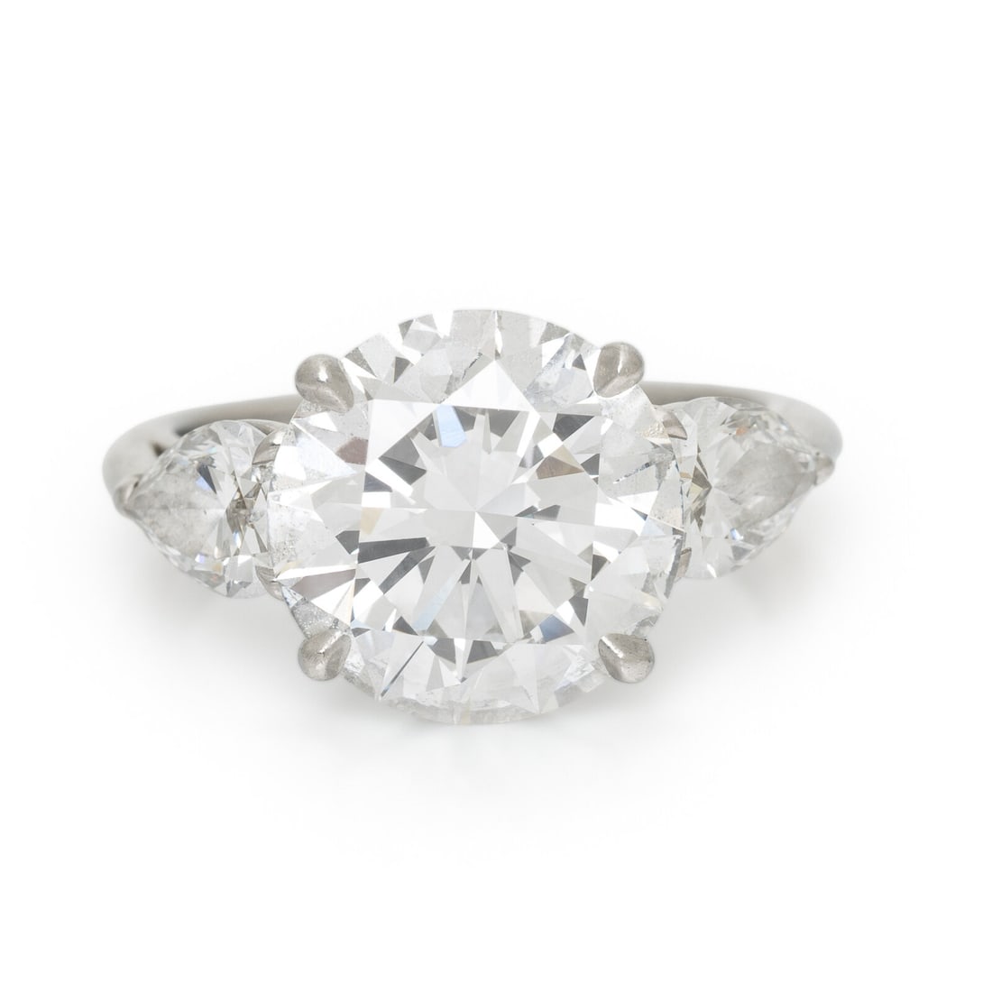 TIFFANY & CO., DIAMOND AND PLATINUM RING: TIFFANY & CO., DIAMOND AND PLATINUM RING Featuring a round diamond weighing 5.19 carats, flanked by pear shape diamonds weighing approximately 1.20 carats total. Mounted in platinum. Ring size 5 3/4.