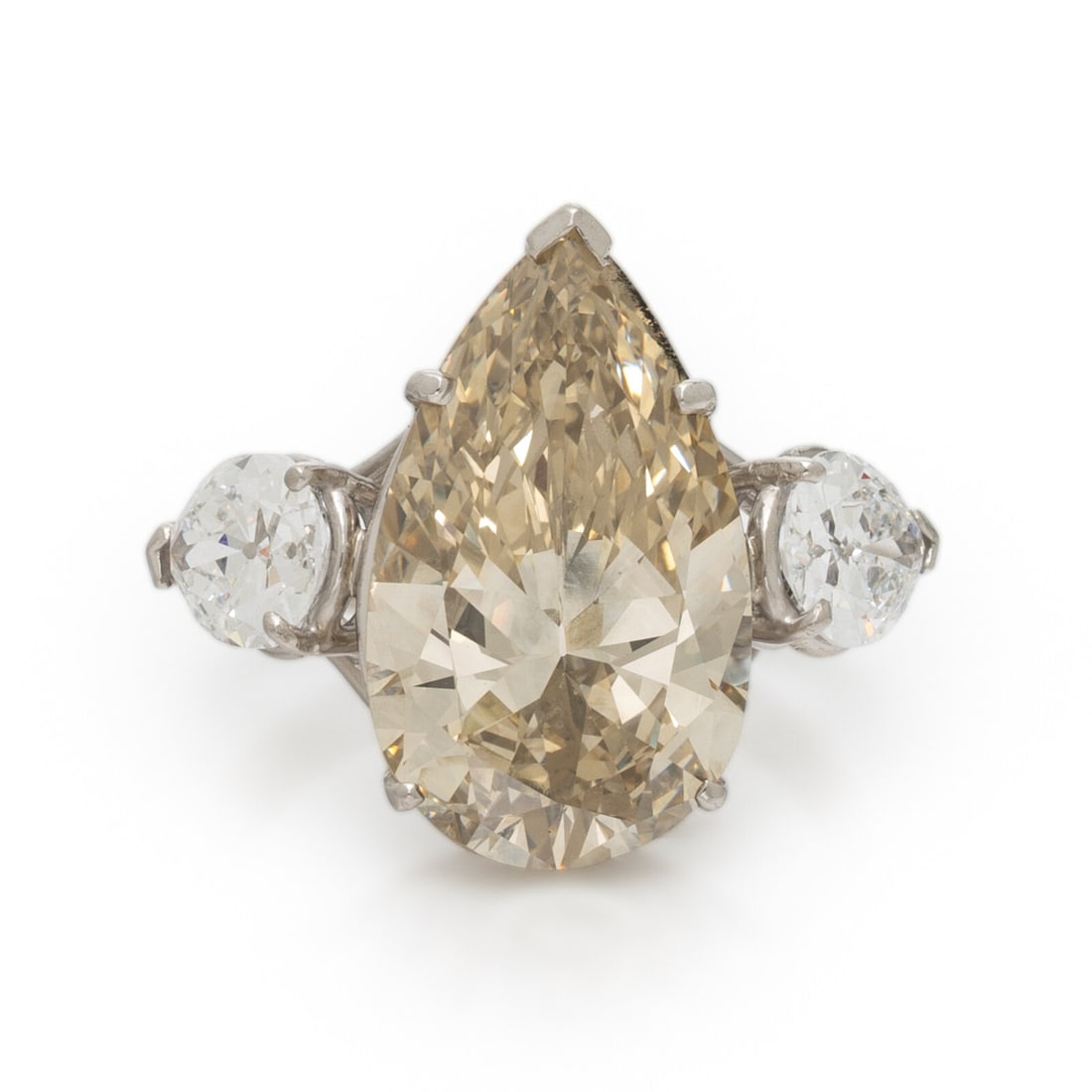 NATURAL FANCY BROWNISH YELLOW PEAR SHAPED DIAMOND AND DIAMOND RING: NATURAL FANCY BROWNISH YELLOW PEAR SHAPED DIAMOND AND DIAMOND RING Featuring a pear shape Fancy Brownish Yellow diamond weighing 8.32 carats, flanked by two pear shape colorless diamonds weighing 1.86