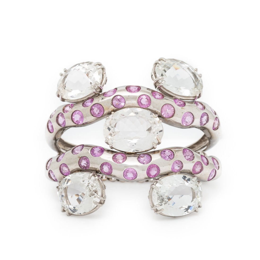 SAZINGG, PINK SAPPHIRE, WHITE TOPAZ, AND WHITE GOLD CUFF BRACELET: SAZINGG, PINK SAPPHIRE, WHITE TOPAZ, AND WHITE GOLD CUFF BRACELET In an abstract design, set with round pink sapphires and oval white topaz. Mounted in 18 karat white gold. 6 1/8 inches inner