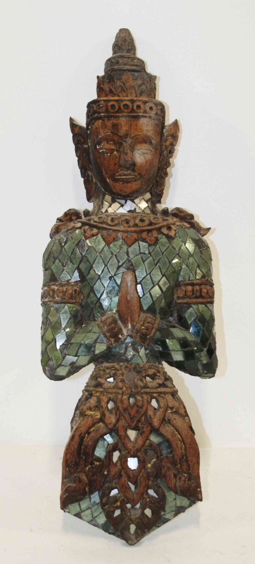A Carved Wood Thai Figure of a Buddha, Height 27 inches: A Carved Wood Thai Figure of a Buddha, depicted with a crown, earrings and a necklace, hands clasped in front in prayer, with mirror inset decoration to garments, possibly an architectural element. He