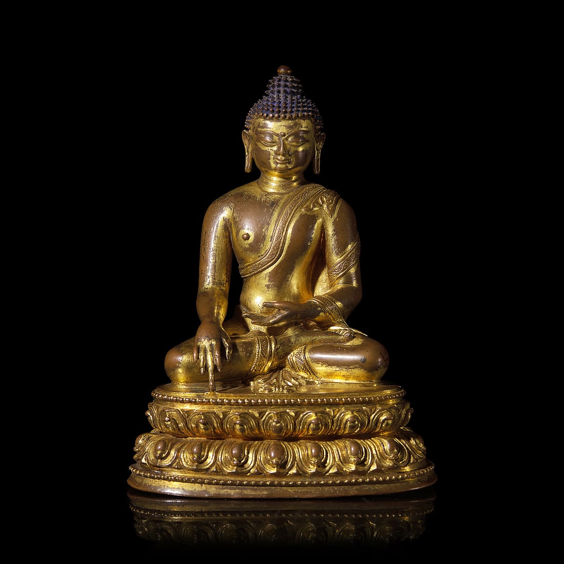 A Tibetan Gilt Copper Alloy Figure of Seated Akshobya, 15th Century 十五世紀: A Tibetan Gilt Copper Alloy Figure of Seated Akshobya, 15th Century 十五世紀 藏傳銅合金阿閦佛 15th Century Elegantly modeled and