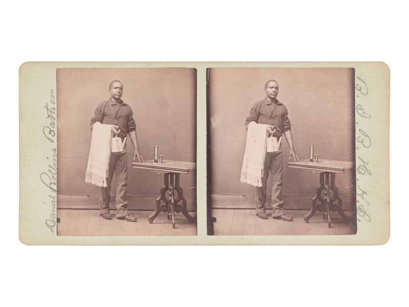 [African Americana] Occupational stereoview of identified African American bather : [African Americana] Occupational stereoview of identified African American bather Stereoview featuring an African American man holding a towel and a kettle, and standing next to a table topped