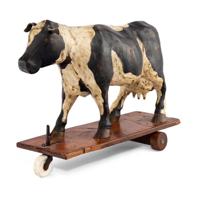 An Early Carved Cow Pulltoy: An Early Carved Cow Pulltoy 19th Century a carved and painted cow pull toy with ceramic and carved wooden wheels.Height 12 x length 14 inches. From an Old Hollywood