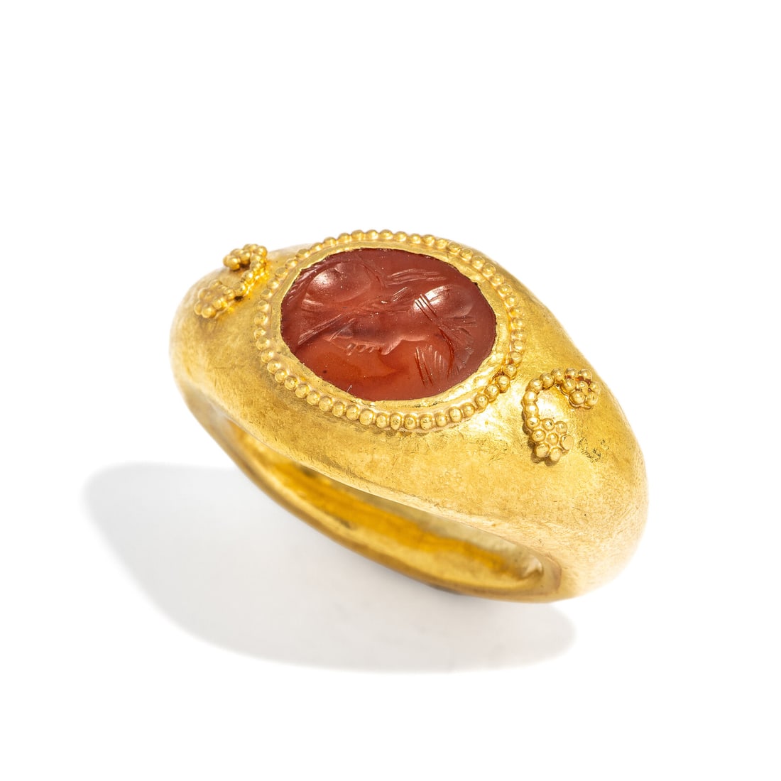 A Roman Gold and Carnelian Ring: A Roman Gold and Carnelian Ring Circa 1st-3rd Century A.D. Width 3.3 cm (1 1/4 inches); Ring size 5 1/4; High karat gold; 11 grams. Provenance: Art Market, New York, 2000s.