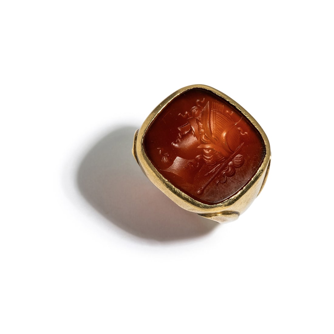 A Neoclassical Gold and Carnelian Finger Ring with the Head of a Goddess: A Neoclassical Gold and Carnelian Finger Ring with the Head of a Goddess Width 2.5 cm (1 inch); Ring size 10; 10 karat gold; 12 grams.