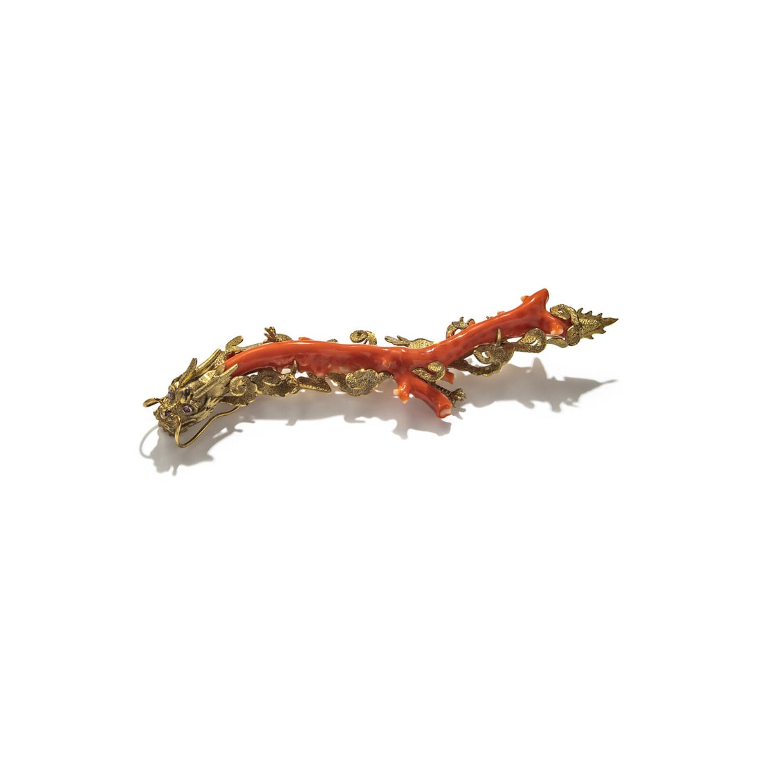 CORAL BRANCH AND YELLOW GOLD DRAGON BROOCH: CORAL BRANCH AND YELLOW GOLD DRAGON BROOCH Coral branch and round rubies. 14 karat yellow gold. 6 7/8 x 1 1/4 inches long. Stamp: 14K. Gross weight: 55.75 dwt. This lot is located in Chicago.