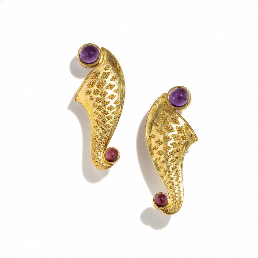 KENT RAIBLE, YELLOW GOLD, AMETHYST, AND GARNET EARRINGS: KENT RAIBLE, YELLOW GOLD, AMETHYST, AND GARNET EARRINGS Round cabochon amethysts and garnets. 18 karat yellow gold. 1 5/8 inches long. Stamp: (Kent Raible maker's mark) 750. Gross weight: 10.50 dwt. P