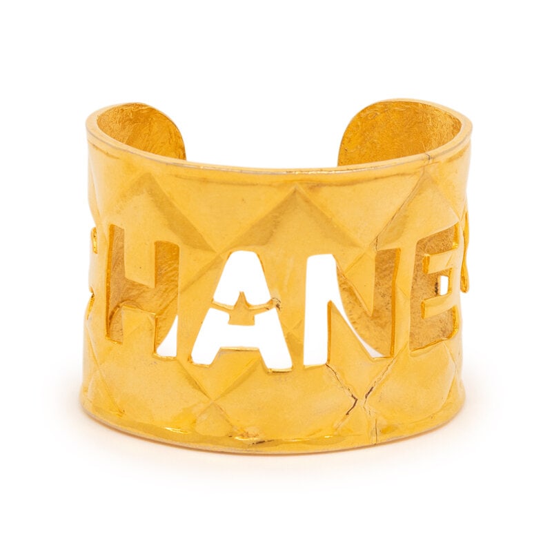 Chanel, Quilted Logo Cuff Bracelet: Chanel, Quilted Logo Cuff Bracelet Cuff bracelet in quilted-effect gold-tone metal, with logo openwork details. Label: Chanel Date: 1980's Country of Origin: France Approximate Measurements: