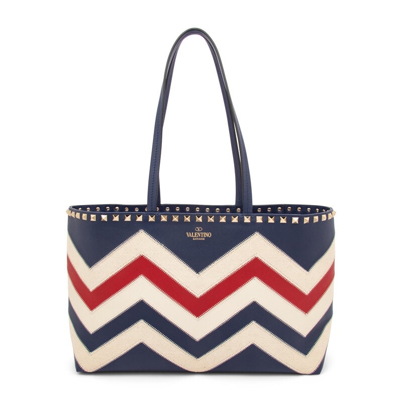 Valentino, Rockstud Small Chevron Tote: Valentino, Rockstud Small Chevron Tote Small Chevron Rockstud tote bag in navy, red, & cream leather and cream canvas with silver-tone Rockstud embellishments. Magnetic snap closure and flat