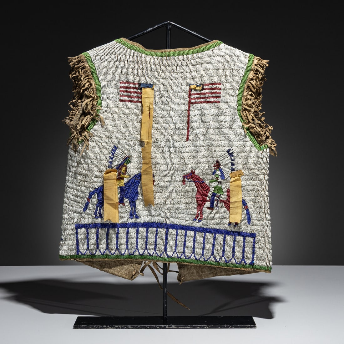 Sioux Beaded Buffalo Hide Pictorial Vest, American Flags and Warriors: Sioux Beaded Buffalo Hide Pictorial Vest, American Flags and Warriors fourth quarter 19th century thread and sinew-sewn; beaded in greasy green, red white-heart, royal blue, and greasy yellow on a whi