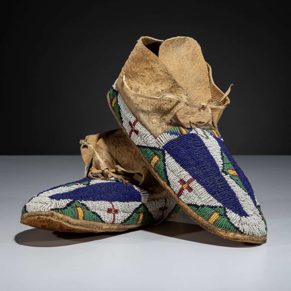 Sioux Beaded Hide Moccasins: Sioux Beaded Hide Moccasins late 19th century sinew-sewn and beaded using colors of dark blue, pea green, cobalt, white, greasy yellow, and white length 11 inches