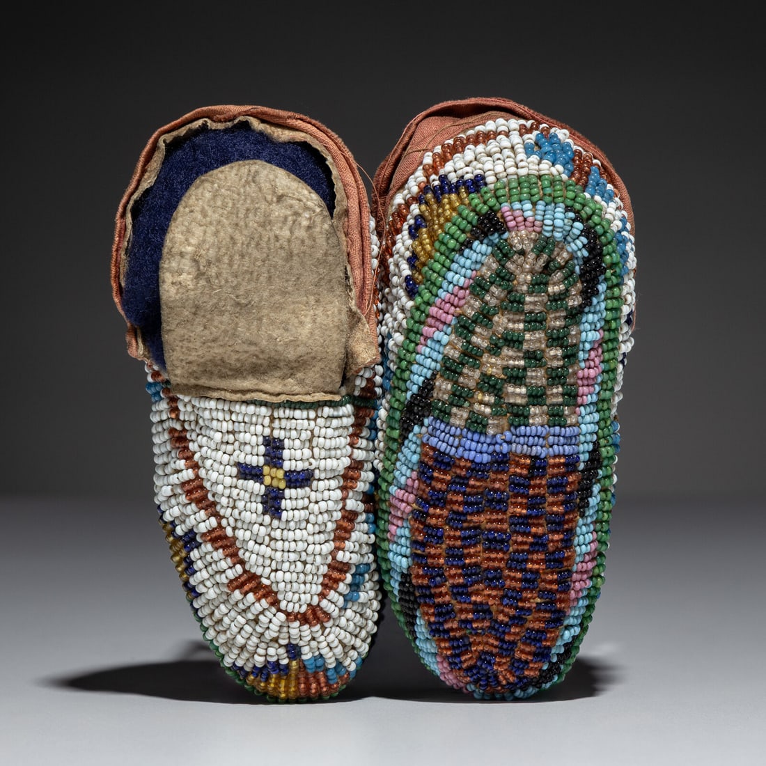 Sioux Child's Fully Beaded Hide Moccasins: Sioux Child's Fully Beaded Hide Moccasins fourth quarter 19th century thread and sinew-sewn; with beadwork in colors of white, pony trader blue, dark blue, amber, dark green, pink, and cobalt; ribbon