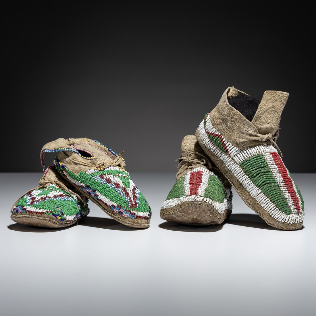 Central and Southern Plains Child's Beaded Hide Moccasins: Central and Southern Plains Child's Beaded Hide Moccasins third quarter 19th century lot of 2, includes: a pair of Sioux/Arapaho buffalo hide moccasins, beaded with colors of red white-heart, pea gree