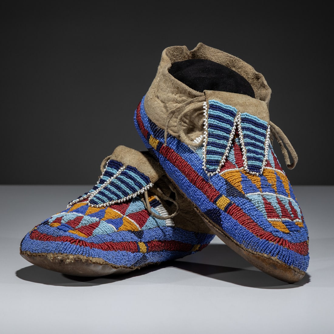 Apsáalooke [Crow] or Hidatsa Beaded Hide Moccasins: Apsáalooke [Crow] or Hidatsa Beaded Hide Moccasins late 19th century sinew-sewn thick, softly-tanned hide; beaded using of colors red white-heart, pumpkin, light and medium blue, white, and