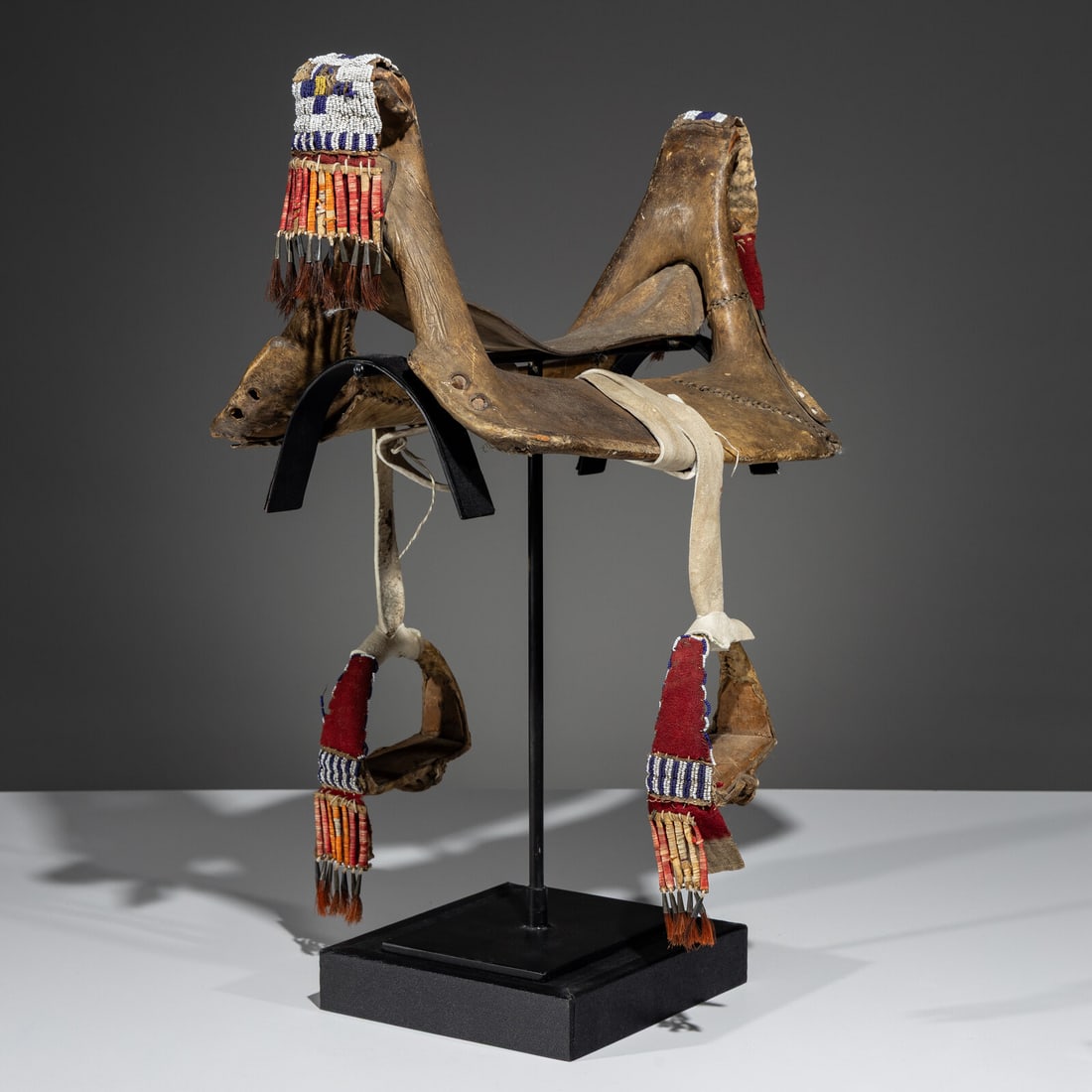 Sioux Child's Beaded Saddle Tree: Sioux Child's Beaded Saddle Tree fourth quarter 19th century rawhide-wrapped wooden tree and stirrups; beaded drops have quilled rawhide slats terminating with horsehair-filled tin cones height