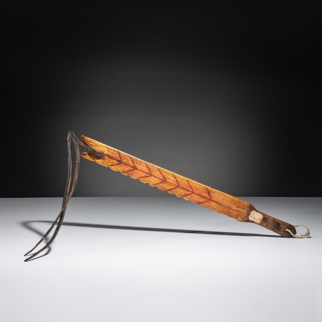 Northern Plains Decorated Wood Quirt: Northern Plains Decorated Wood Quirt fourth quarter 19th century possibly Arapaho, flattened form with scalloped edge; feather-like design on one side and parallel undulating bands on opposite; red