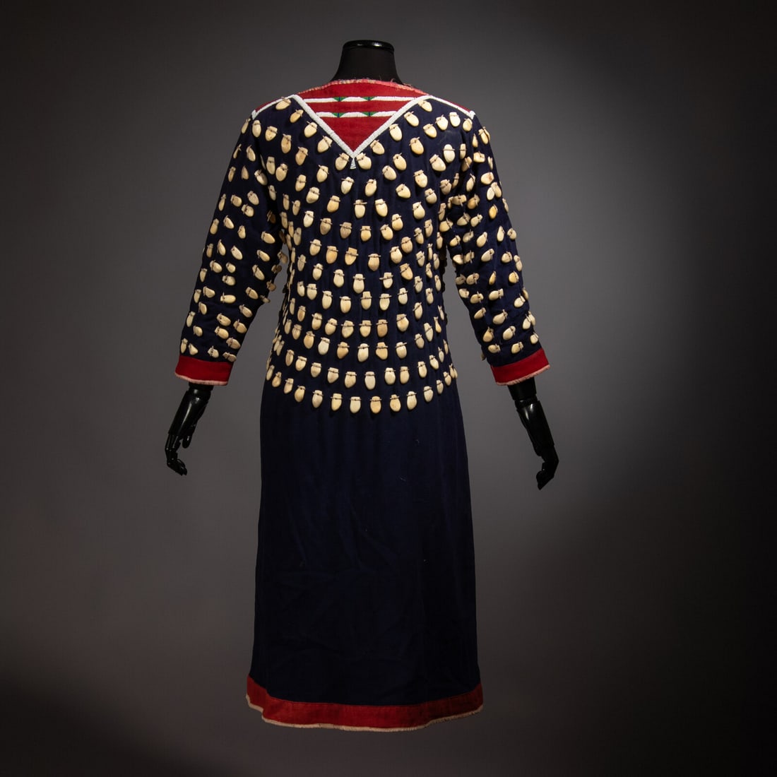 Nez Perce Elk Tooth Dress: Nez Perce Elk Tooth Dress ca 1900 thread-sewn navy trade wool; elk teeth dot the yoke, arms, and upper bodice of the dress and are attached using hide thongs; red trade wool and ribbon on cuffs and