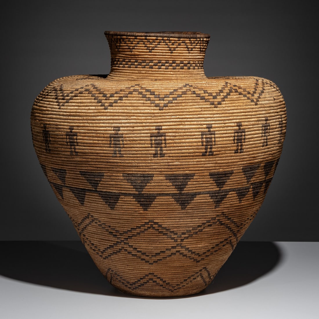 Western Apache Basketry Olla, with Human Figures: Western Apache Basketry Olla, with Human Figures early 20th century with 18 humans around the shoulder height 21 inches x diameter 20 inches From an Old Hollywood Family This lot is located in Chicago