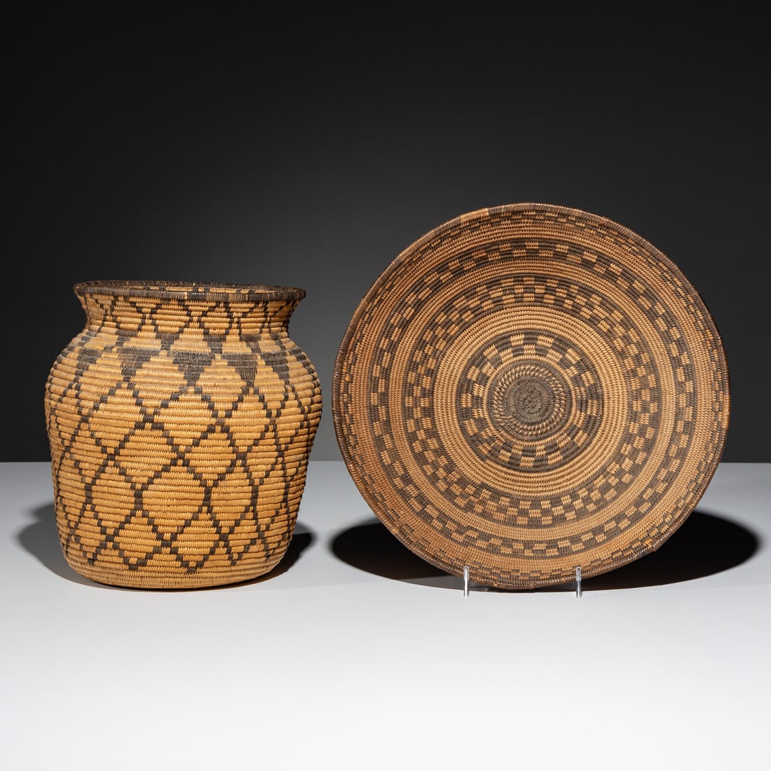 Apache Baskets: Apache Baskets early 20th century lot of 2, includes: an olla, height 8-3/4 inches x diameter 8-1/2 inches a basket with checkered bands, height 4 inches x diameter 11-1/4 inches This lot is