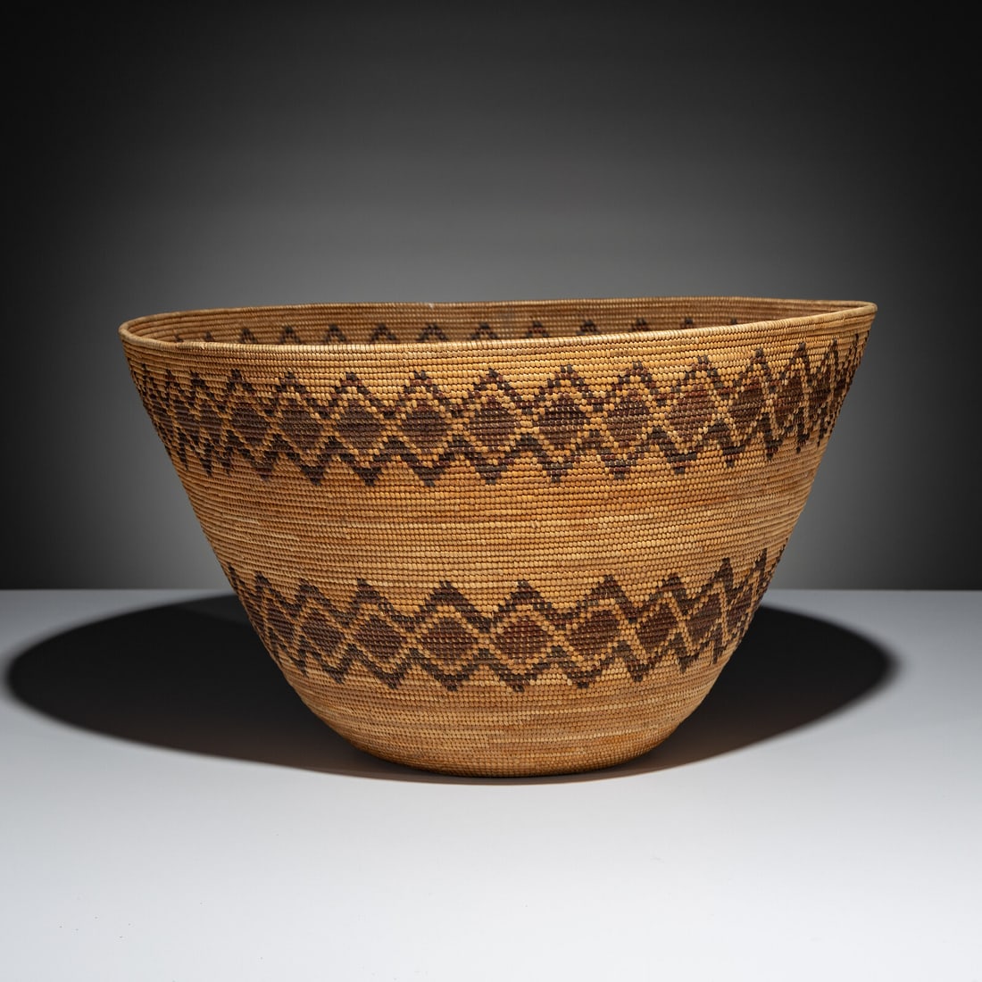 Yokut Polychrome Basket, with Rattlesnake Bands: Yokut Polychrome Basket, with Rattlesnake Bands early 20th century height 10 inches x diameter 17 inches From an Old Hollywood Family This lot is located in Chicago.