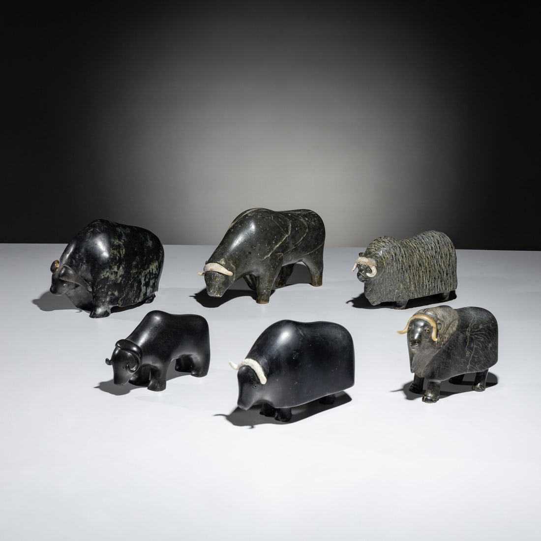 Inuit Carved Soapstone Muskoxen Herd: Inuit Carved Soapstone Muskoxen Herd lot of 6, includes: attributed Fred Iyak Trimble (Inuvialuit, b. 1961), signed in syllabics, with Igloo Tag, height 5 inches x length 8 inches x width 3 inches Laz