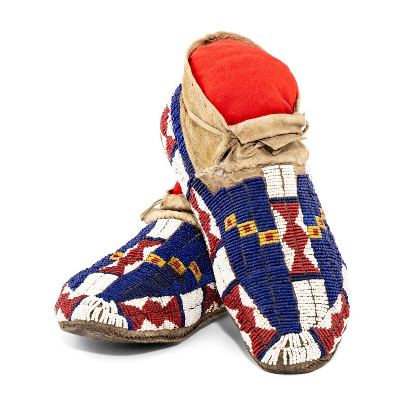 Arapaho Beaded Hide Moccasins: Arapaho Beaded Hide Moccasins late 19th century sinew-sewn with some later thread-sewn patches on cuff; beaded bowtie design in colors of navy blue, red white-heart, white, and a light greasy yellow 