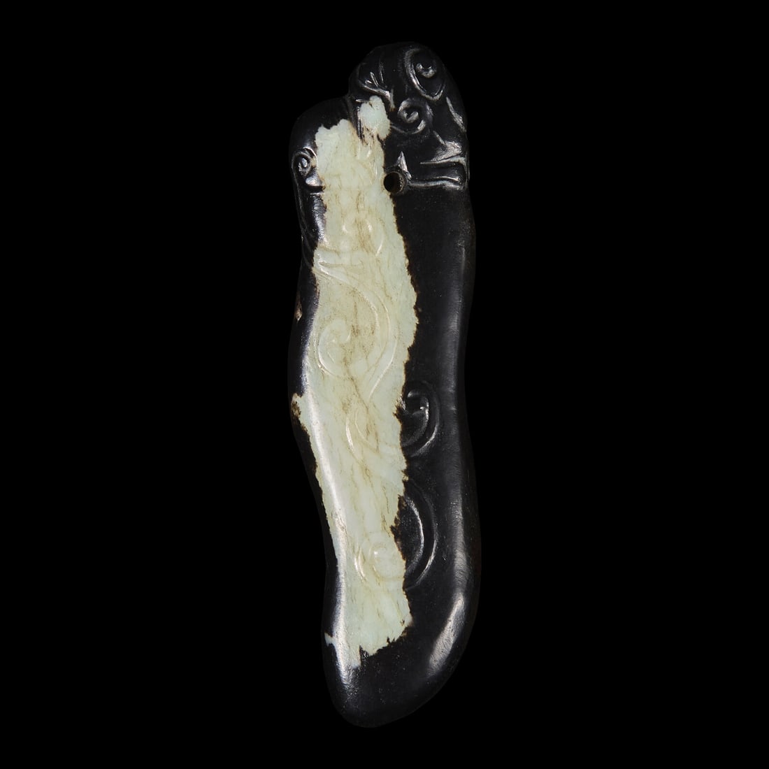 A Black and White Jade Pendant, Qing Dynasty 清 黑白玉珮: A Black and White Jade Pendant, Qing Dynasty 清 黑白玉珮 Decorated with low-relief motifs, possibly featuring a mythical beast. Length 3 1/2 in., 8.9 cm. This lot is loca