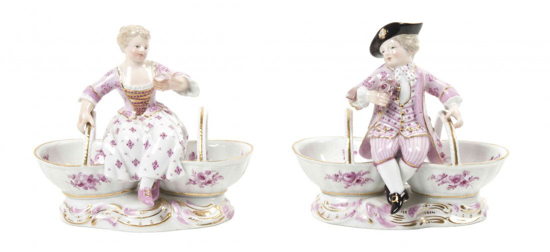 A Pair of Meissen Porcelain Figural Sweetmeat Dishes, H: A Pair of Meissen Porcelain Figural Sweetmeat Dishes, depicting a boy and girl in 18th century attire resting atop the segmented bowls, having crossed swords mark in blue underglaze with further impre