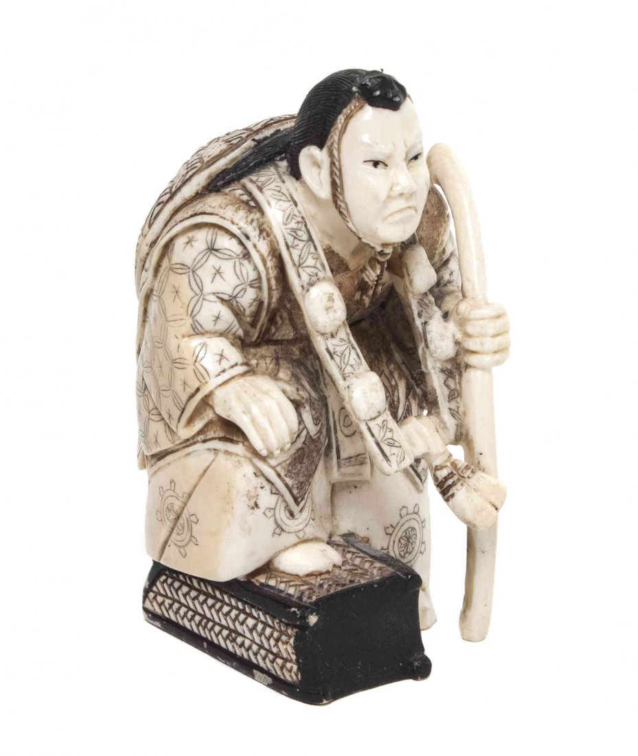 A Japanese Carved Ivory Netsuke, Height 2 3/4 inches.: A Japanese Carved Ivory Netsuke, depicting a man holding a wood staff with his foot resting on a box, signed to the underside. Height 2 3/4 inches. Property from the Estate of Henry Rosenberg, Hollywo