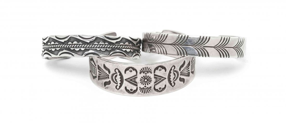 A Collection of Three Navajo Sterling Silver Bracelets,: A Collection of Three Navajo Sterling Silver Bracelets, each having stamped decoration, one marked SY for Steve Yellowhorse, and Sterling, one marked ESS for Edison Smith, the third, unmarked. Larges