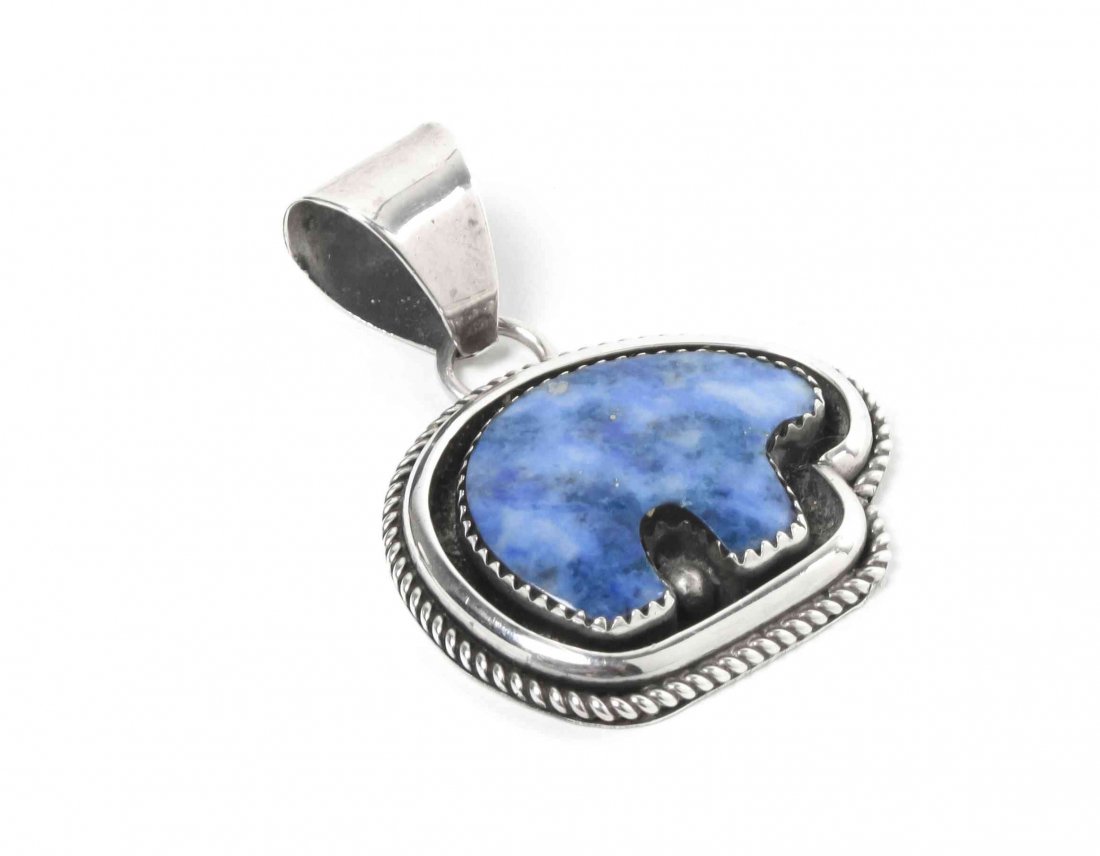 A Navajo Sterling Silver and Lapis Pendant, Robert and : A Navajo Sterling Silver and Lapis Pendant, Robert and Noreen Kelly, lapis in the shape of a bear set in shadow box mount, marked Robert and Noreen Kelly, surrounding a feather hallmark and .925. Heig